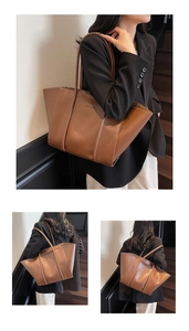 Detail of a brown large capacity tote bag with embossed fashion text and pebble texture