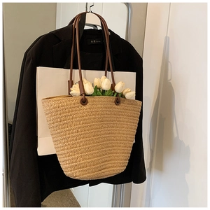 Detailed weave texture of beige straw tote bag with brown leather handles and tulip