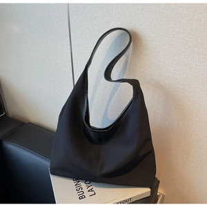 Detailed view of black minimalist canvas tote bag on a prop book in indoor lighting