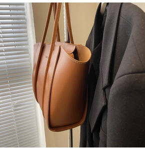 Close-up of vintage brown leather tote bag with fine white stitching and FASHION logo