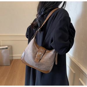Détail du sac hobo avec patchwork de daim marron et grande boucle décorative en métal
