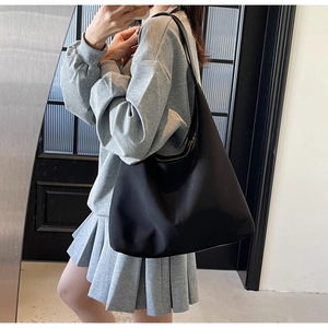 Detailed mirror selfie of a large black canvas tote bag with a minimalist wide shoulder strap