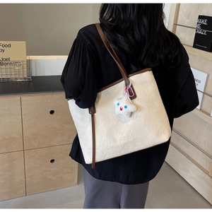 Close-up of embossed floral pattern on beige tote bag with a star plush pendant