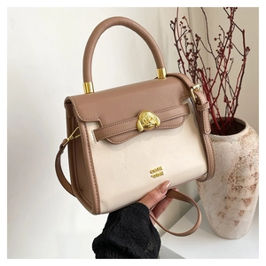 Detail of contrast handbag with gold bulldog clasp and brown faux leather flap cover