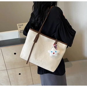 Detail of cream large tote bag with brown straps and embossed floral patterns
