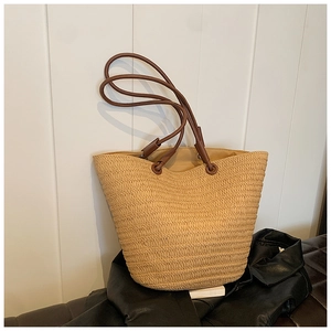Close-up of woven straw texture and slim leather handles on this large summer tote bag