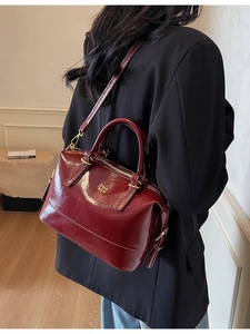 Elegant wine red glossy leather Boston bag shown from back view on model's shoulder