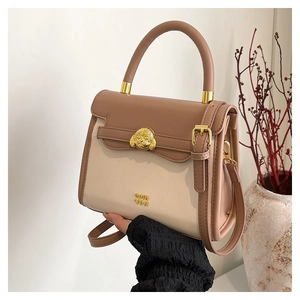 Detail of a beige and pink crossbody bag with a golden dog emblem and leather handles