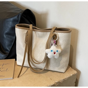 Close-up of beige embossed tote bag with brown straps and cute star-shaped plush pendant