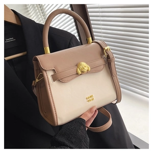 Detail of elegant two-tone crossbody bag with golden dog charm and adjustable strap
