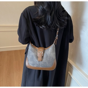Détail d'un sac hobo en toile grise avec garnitures en cuir marron et boucle en métal argenté