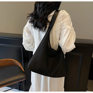 Minimalist black large capacity canvas hobo tote bag worn as a shoulder shopping bag