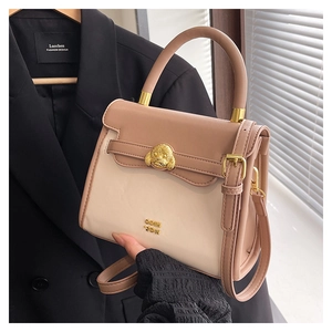 Detail of a beige and pink crossbody bag with a golden poodle head clasp and logo