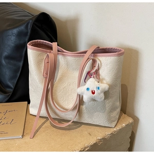 Detail of cream tote bag with embossed Chinese characters and star plush pendant