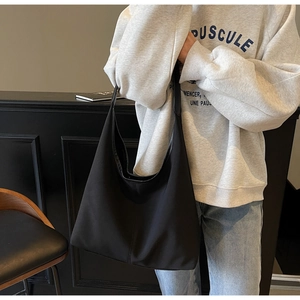 Close-up of black matte canvas tote bag with vertical stitching and wide shoulder strap