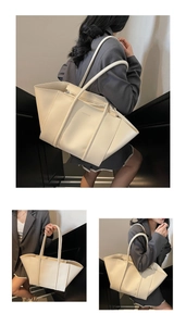 Detailed view of cream tote bag with FASHION embossed texture and zipper closure
