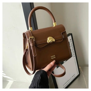 Detail of dark brown leather crossbody bag with round handle and gold metal dog ornament