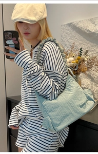 Detalle del bolso plisado azul claro con correa de volantes mostrado en un selfie de espejo