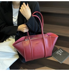 Close-up of burgundy tote bag with white contrast stitching and FASHION embossed logo