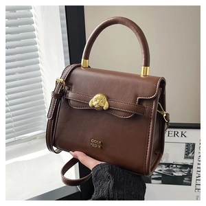 Detail of vintage dark brown leather crossbody bag with golden dog head emblem hardware