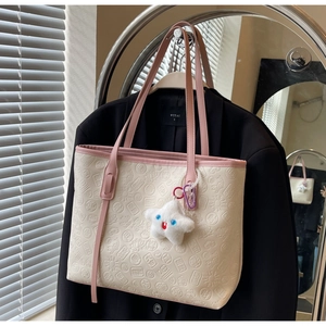 Detail of beige tote bag with embossed traditional motifs and pink long handles