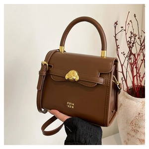 Detail of dark brown leather handbag featuring gold dog-shaped buckle and metal logo