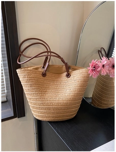 Macro detail of natural straw tote bag featuring woven texture and brown faux leather straps