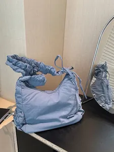 Detalle del bolso azul con correa fruncida y cordones de ajuste laterales ajustables