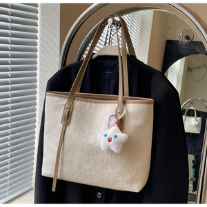 Detail of cream tote bag with embossed Chinese patterns and a star plush charm