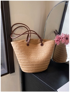 Detailed view of woven straw tote bag with brown leather handles and natural fiber texture