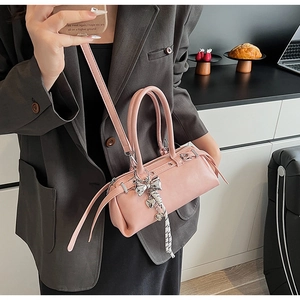 Pink Boston bag with silver bow charm and adjustable strap shown on a gray suit outfit