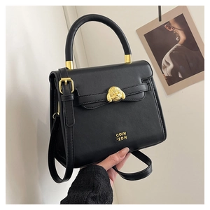Close-up of black crossbody bag featuring a golden poodle-shaped lock and handle detail