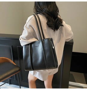 Close-up of black tote bag with FASHION logo and smooth faux leather texture