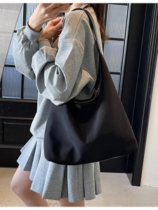 Minimalist large capacity black canvas tote bag shown in a stylish shoulder carry pose