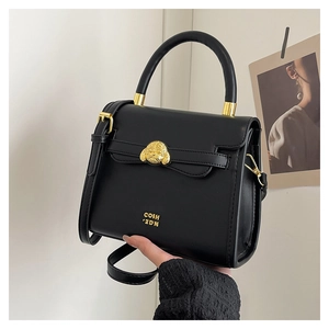 Detail of black leather handbag featuring golden dog-head sculpture and gold brand logo