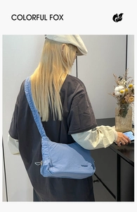 Bolso bandolera de nailon azul con correa ancha mostrado en modelo para uso diario moda