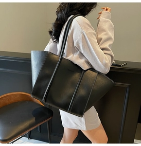 Detail of large black tote bag with white contrast stitching and embossed FASHION text