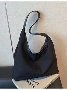 Large black minimalist canvas tote bag with leather trim on white books backdrop