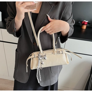 Detail view of a cream Boston bag with silver hardware and heart charm decoration