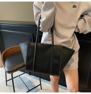 Detail of black leather tote bag with white contrast stitching and FASHION embossed logo