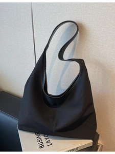 Minimalist black canvas hobo tote bag for daily commute shown on a white book decor
