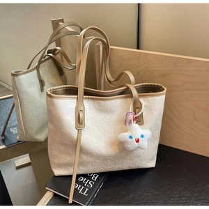 Detail of white PU tote bag featuring traditional embossed patterns and plush star charm