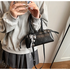 Close-up of black Boston bag with silver heart bow charm and polished metal eyelets