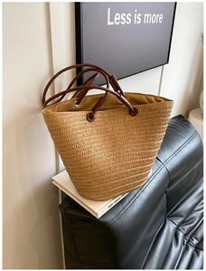 Macro detail of natural straw woven tote bag texture with brown handles on a book