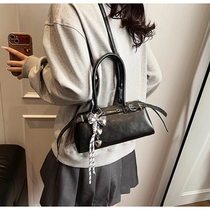 Detail of black faux leather Boston bag with silver heart charms and buckle accents