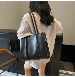 Close-up of black tote bag with white contrast stitching and FASHION embossed detail