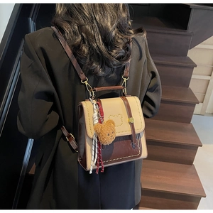 Detail van tweekleurige vintage mini-rugzak met berenvormige flap en pluche hanger op trap