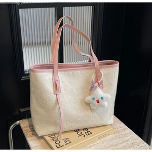 Detail of cream tote bag with pink trim, embossed Chinese characters, and star plush charm