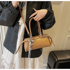 Caramel retro boston bag with metal eyelets and silver bow charm styled with an outfit