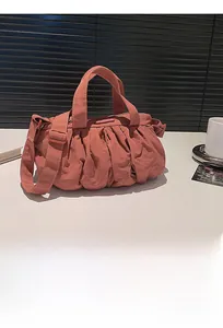 Detail einer gefalteten Nylon-Wolkentasche in Korallenrosa mit verstellbarem Schultergurt